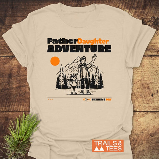 Father/Daughter Adventure T-Shirt featuring a bearded dad and daughter in a mountain setting with an orange sun, emphasizing outdoor bonding. Crafted from soft cotton for comfort and durability.