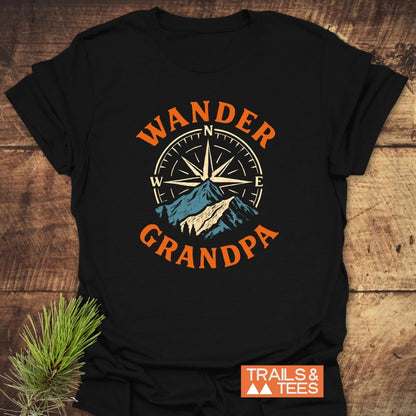 Wander Grandpa T-Shirt flat-lay featuring a compass rose and mountain design. Crafted from soft, ring-spun cotton for comfort, it showcases orange lettering and a durable print by Trails & Tees.