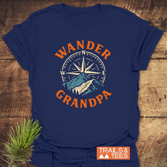 Wander Grandpa T-Shirt features a stylized compass and mountains, with bold orange WANDER and GRANDPA text. Includes a small TRAILS & TEES logo, ideal for outdoor enthusiasts.