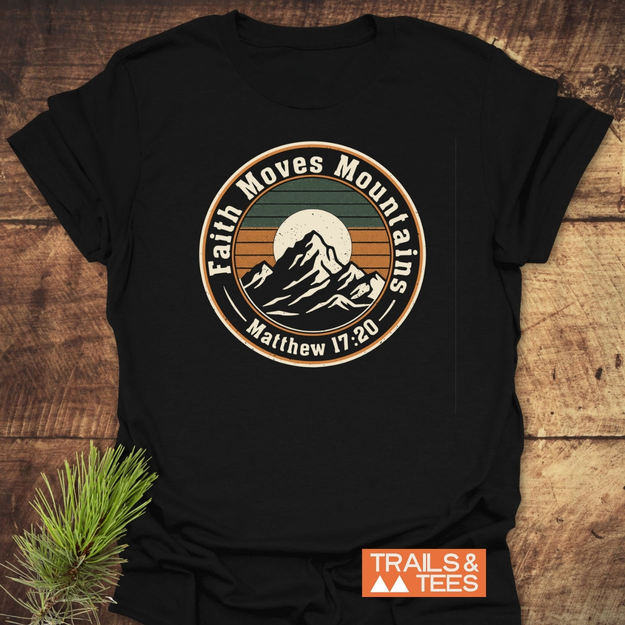 Faith Moves Mountains T-Shirt featuring a retro mountain graphic and Matthew 17:20 scripture, crafted from soft cotton for comfort. Includes Trails & Tees logo, designed for outdoor enthusiasts.