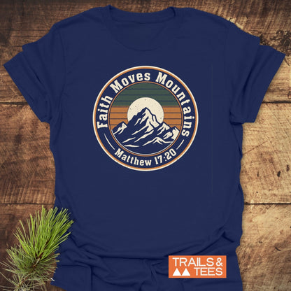 Faith Moves Mountains T-Shirt with a vintage mountain graphic and motivational quote on a rustic wooden surface. Features durable print on soft, lightweight cotton, designed for everyday adventure and outdoor enthusiasts.