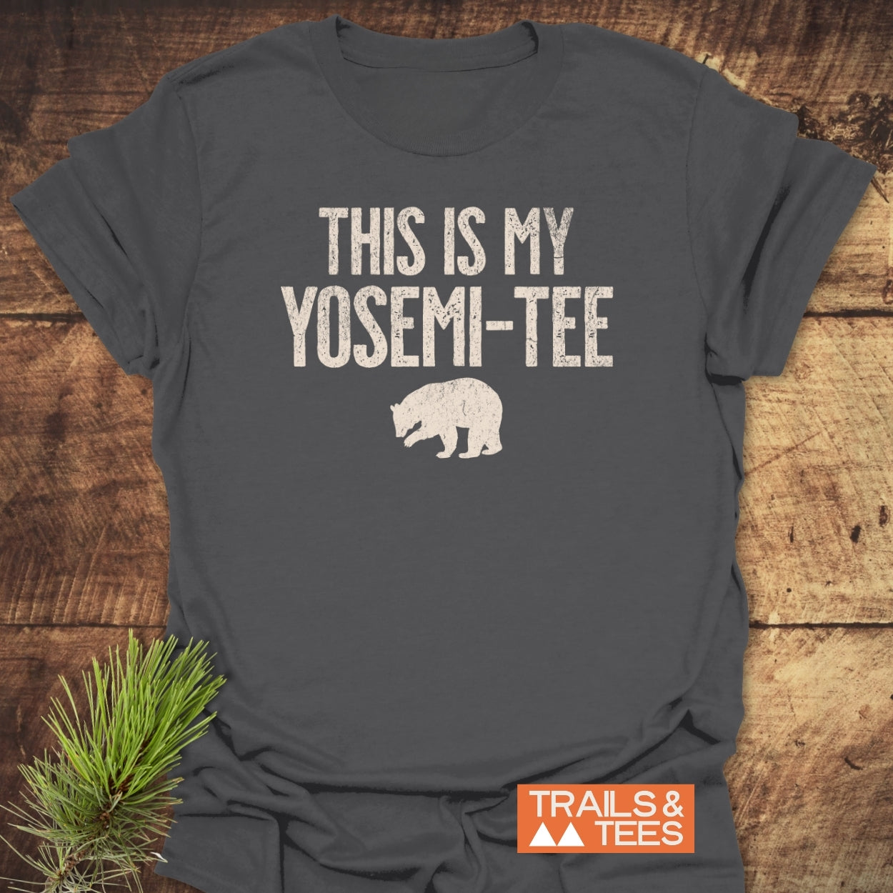 Dark-gray This Is My Yosemi-Tee Funny T-Shirt with off-white slogan and bear silhouette, laid on wood. Features durable print, Trail & Tees logo, emphasizing outdoor comfort and adventure.