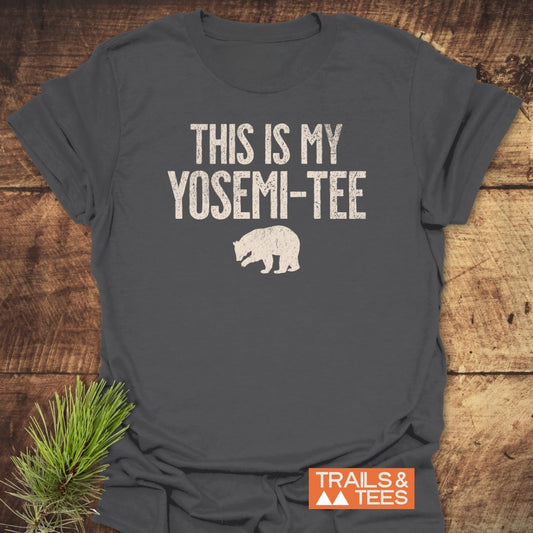 Dark-gray This Is My Yosemi-Tee Funny T-Shirt with off-white slogan and bear silhouette, laid on wood. Features durable print, Trail & Tees logo, emphasizing outdoor comfort and adventure.