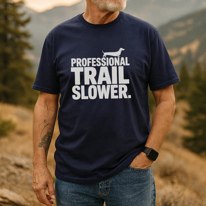 Man outdoors wearing the Trail Slower Dachshund T-Shirt, showcasing a navy tee with “Professional TRAIL SLOWER” text and dachshund silhouette, paired with jeans, highlighting casual, adventure-ready style.