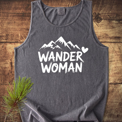Wander Woman Comfort Colors 9360 Tank Top in heather-gray, featuring a white stylized mountain graphic and WANDER WOMAN text on the front, laid on wood with a pine sprig accent.