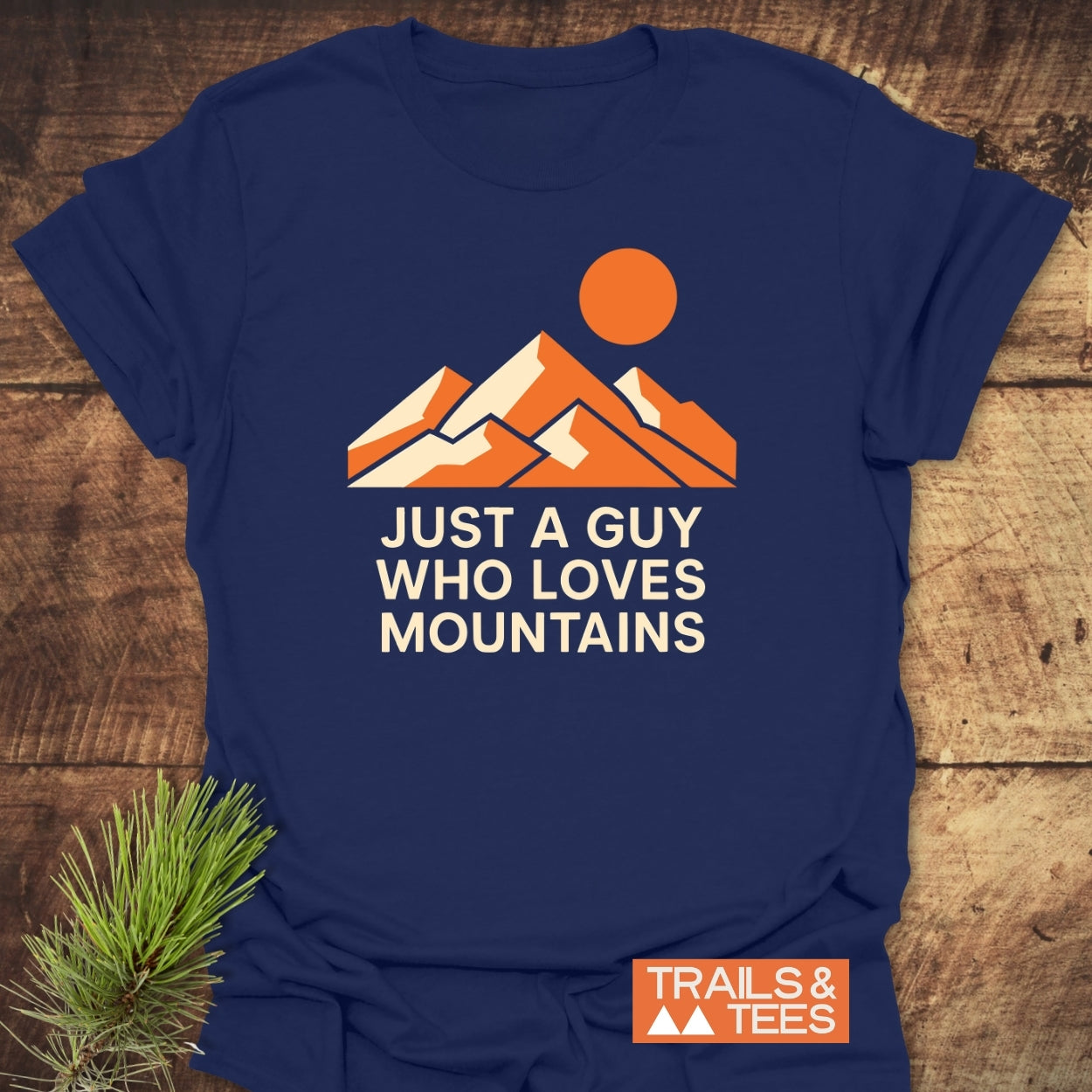 Mountain Love T-Shirt features stylized mountains and sun graphic with JUST A GUY WHO LOVES MOUNTAINS text. Crafted from soft cotton, it promises comfort and durability for outdoor enthusiasts.