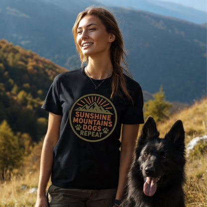 Young woman on a mountain trail wearing the Sunshine Mountains Dogs Badge T-Shirt with a mountain-sun graphic, accompanied by a large black dog, capturing the shirt's outdoor spirit and comfort.