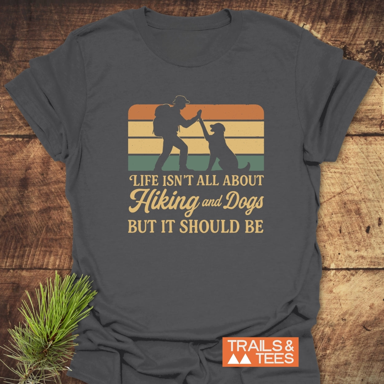 Hiking And Dogs T-Shirt featuring a retro graphic of a hiker high-fiving a dog, complemented by the phrase Life isn’t all about Hiking and Dogs but it should be.
