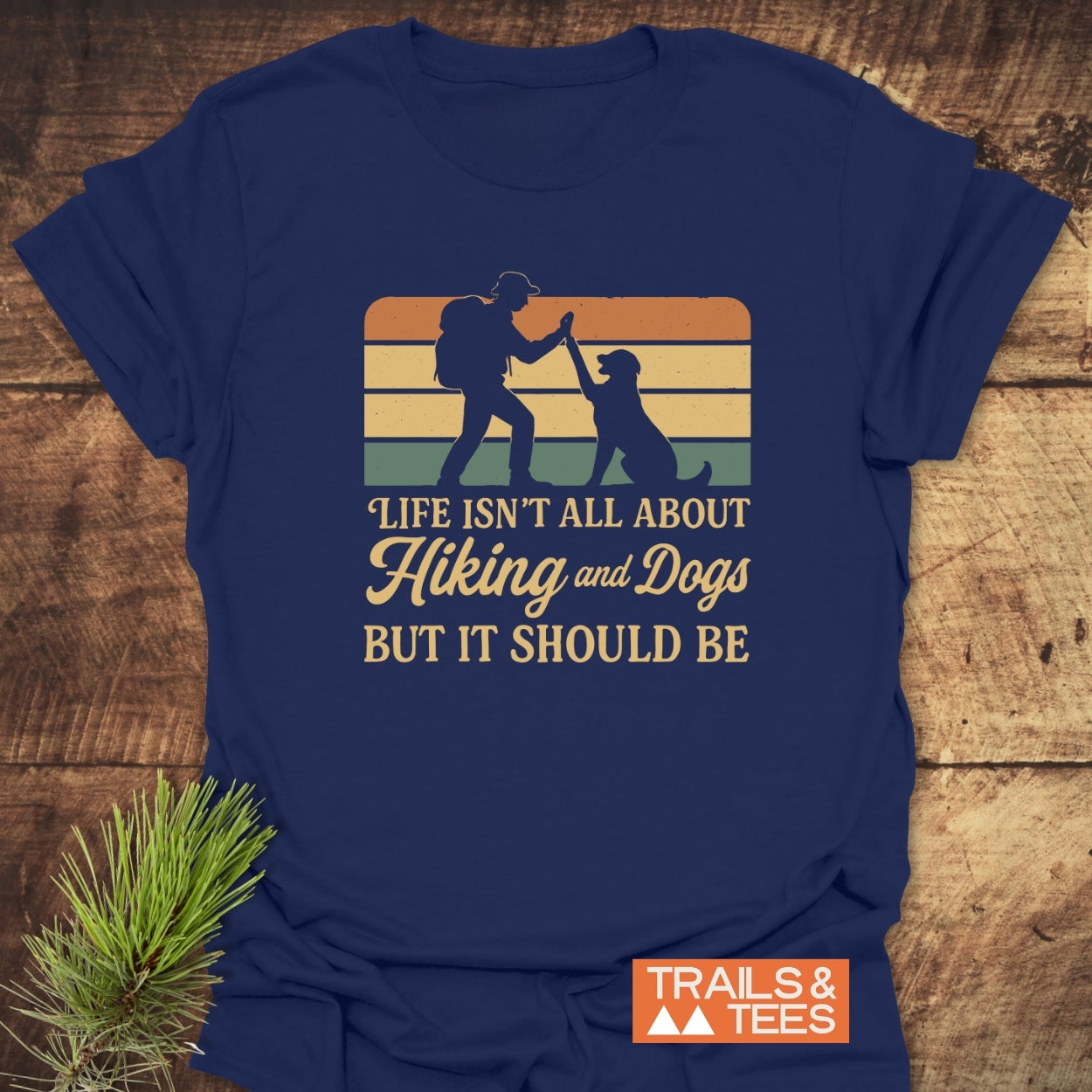 Navy-blue Hiking And Dogs T-Shirt featuring a vintage-style graphic of a hiker and dog with sunset stripes, and the slogan, “Life isn’t all about Hiking and Dogs But it should be.”