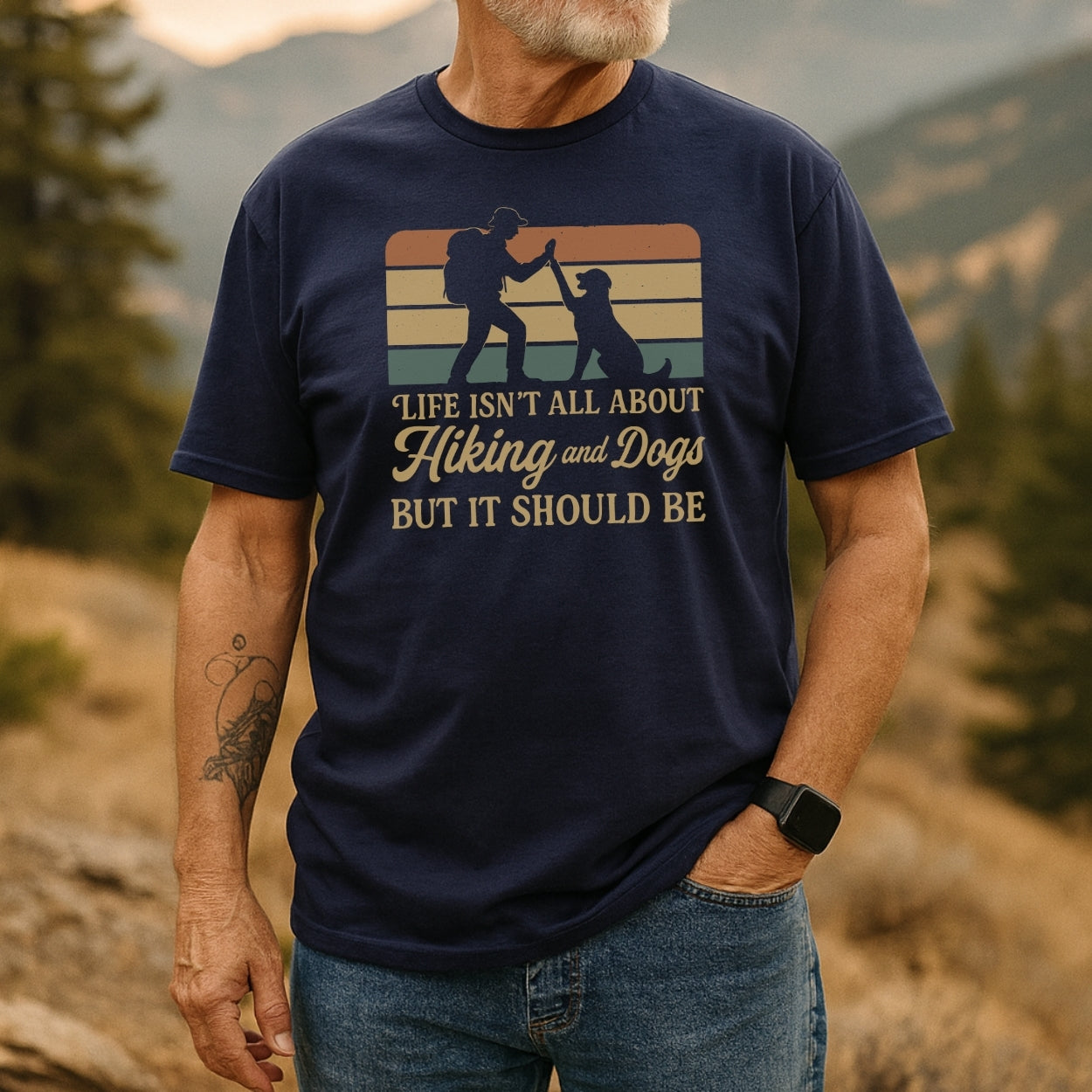 Older man in a hilly forest setting wearing the Hiking And Dogs T-Shirt, featuring a graphic of a hiker and dog with the slogan, promoting outdoor adventure and comfort.