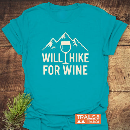 Will Hike For Wine T-Shirt featuring a mountain and wine glass graphic. Includes “TRAILS & TEES” logo. Enhanced comfort with lightweight cotton, showcasing outdoor enthusiasm. Pine sprig accentuates the theme.