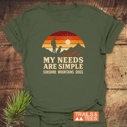 Simple Needs Vintage T-Shirt featuring a retro graphic of a person and dog on a mountain ridge at sunset. Slogan reads, “MY NEEDS ARE SIMPLE: SUNSHINE MOUNTAINS DOGS.” Includes TRAILS & TEES logo.