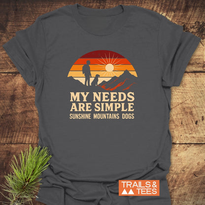 Simple Needs Vintage T-Shirt features a sunset scene and slogan My needs are simple: Sunshine Mountains Dogs on soft, dark-gray cotton, emphasizing outdoor adventure. Durable and sustainably printed.