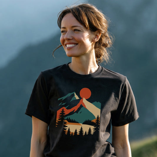 Woman wearing Mountain Sunset Graphic T-Shirt with stylized landscape of sun, mountains, and trees, embodying trail-tested comfort and timeless design, perfect for outdoor enthusiasts.