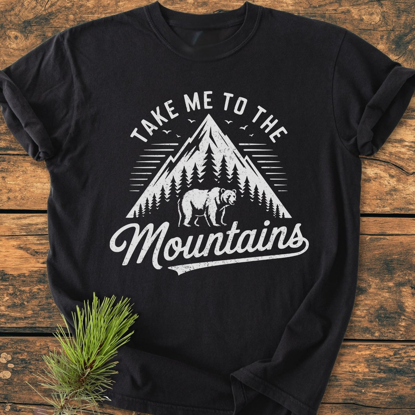 Take Me To The Mountains - Vintage Wash Tee features a mountain and bear graphic on a soft, garment-dyed black T-shirt, styled for comfort and durability with a relaxed fit.