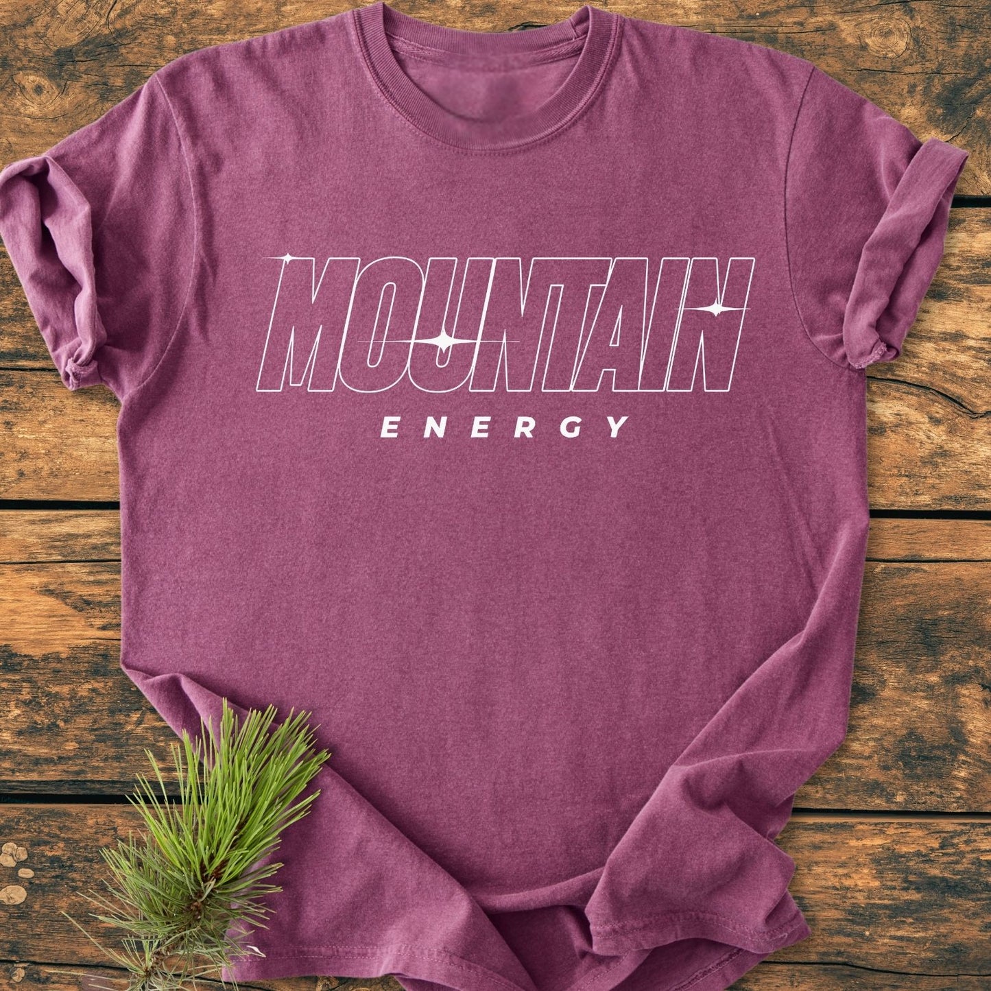 Heathered purple Mountain Energy Vintage Wash Tee flat-laid with bold MOUNTAIN and ENERGY text, featuring a pine sprig accent, showcasing its relaxed fit and durable, customizable design.