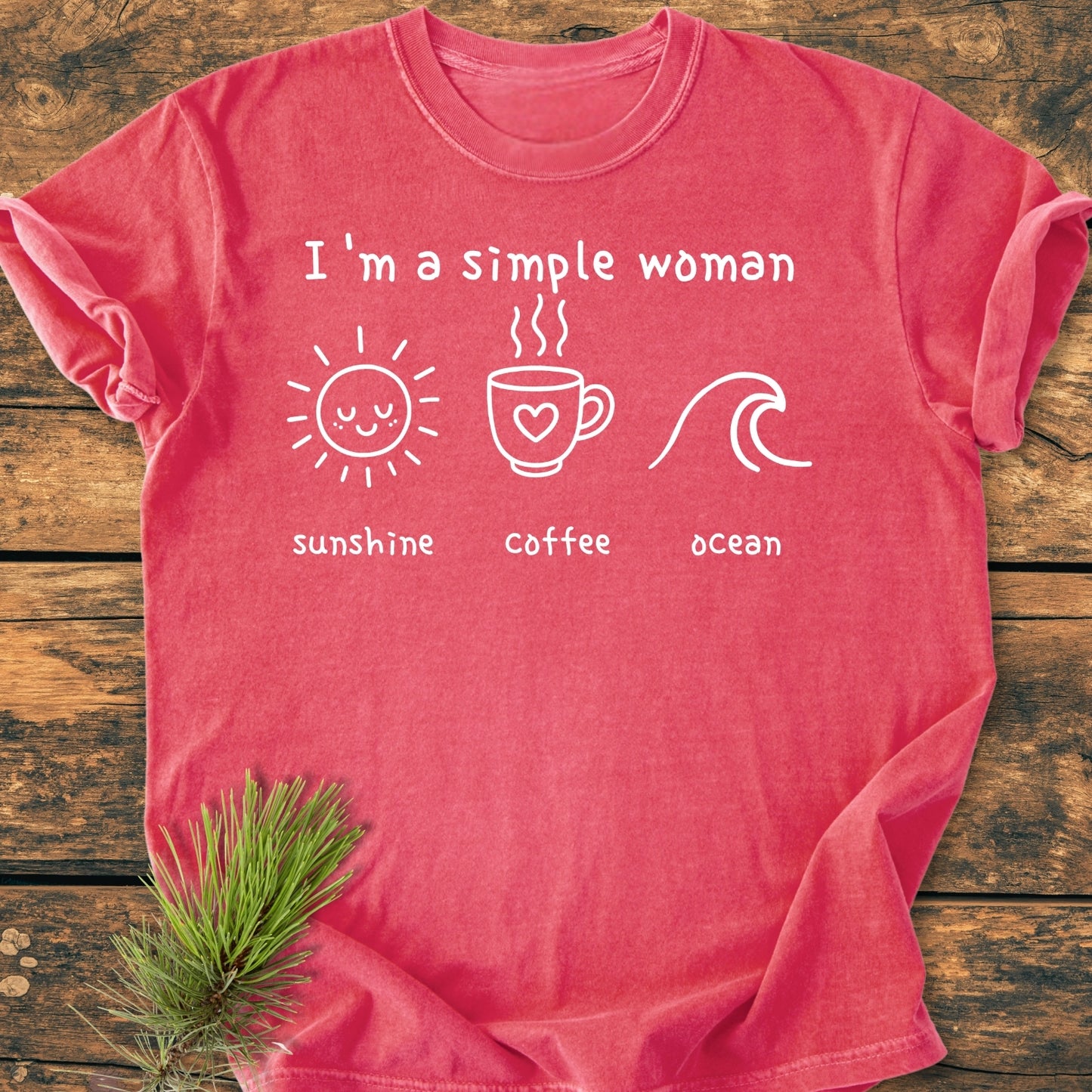 I'm A Simple Woman, Sunshine Coffee Ocean - Vintage Wash Tee features a coral-red T-shirt with white slogan and icons of sun, coffee, and ocean, laid on rustic wood with pine sprig.