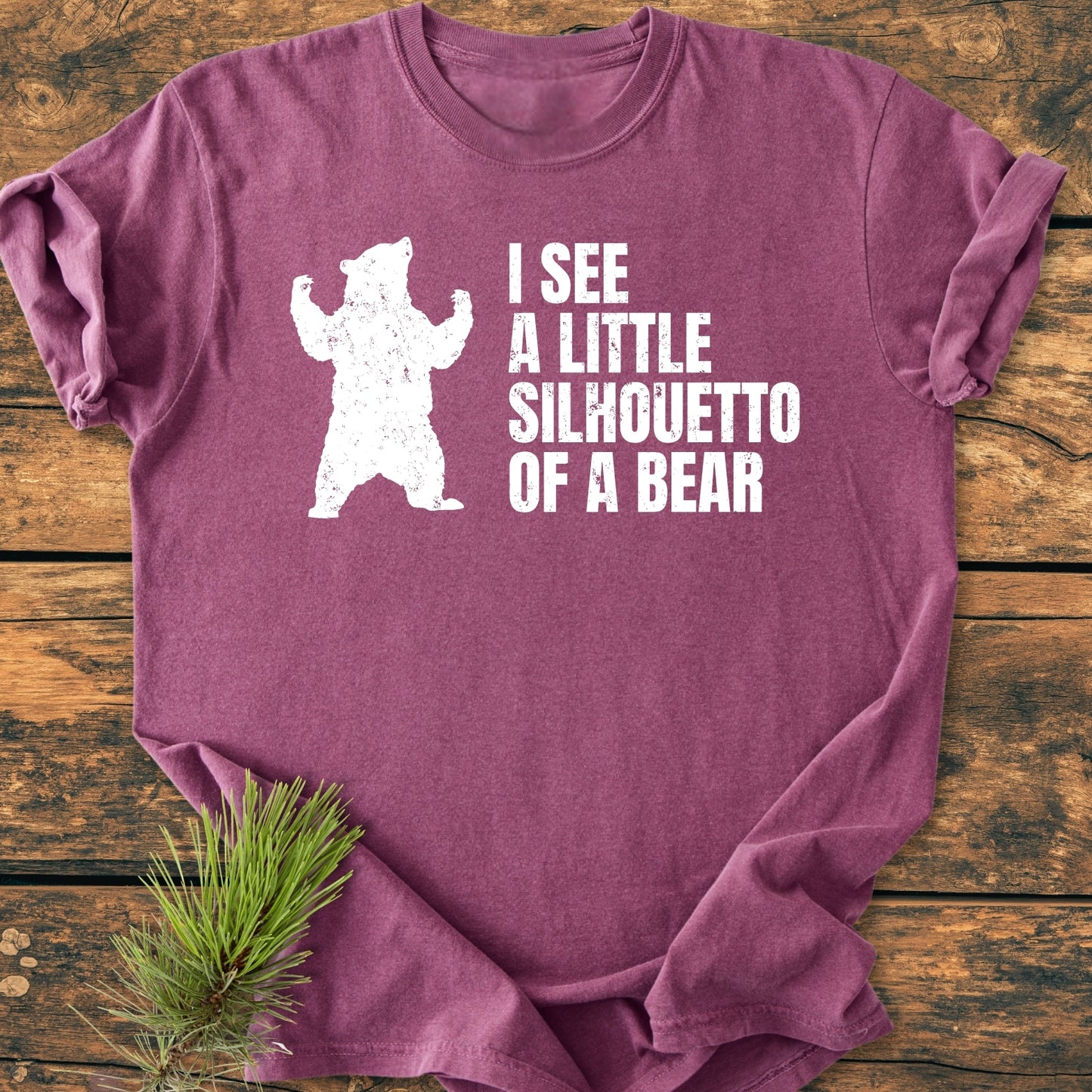 Heathered purple I See A Little Silhouetto Of A Bear - Vintage Wash Tee with distressed bear print and text, laid flat on wood, pine sprig beside it. Soft, relaxed fit, 100% ring-spun cotton.