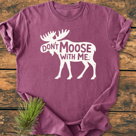 Don't Moose With Me - Vintage Wash Tee displayed on rustic wood, features a white moose silhouette with a slogan. Made from soft, garment-dyed fabric, showcasing a relaxed fit and durable stitching.