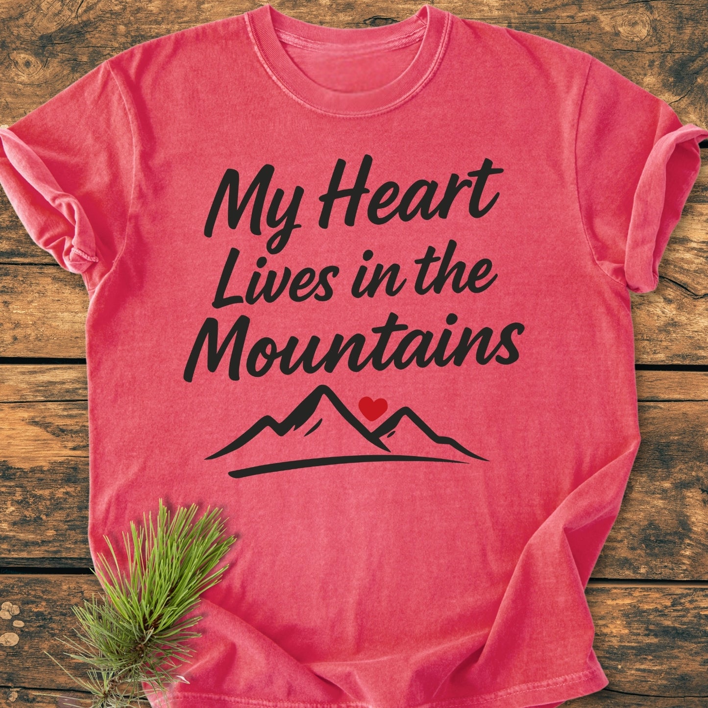 My Heart Lives In The Mountains - Vintage Wash Tee features a black-script slogan and mountain outline with a red heart on a soft, relaxed-fit, garment-dyed T-shirt, complemented by a pine sprig.