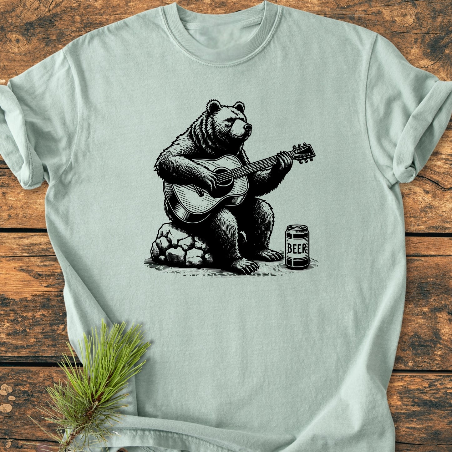 Bear Playing Guitar - Vintage Wash Tee features a detailed bear illustration with a guitar and beer can, on a laid-flat, soft-washed, pale greenish-gray T-shirt, embodying a cozy, relaxed fit.