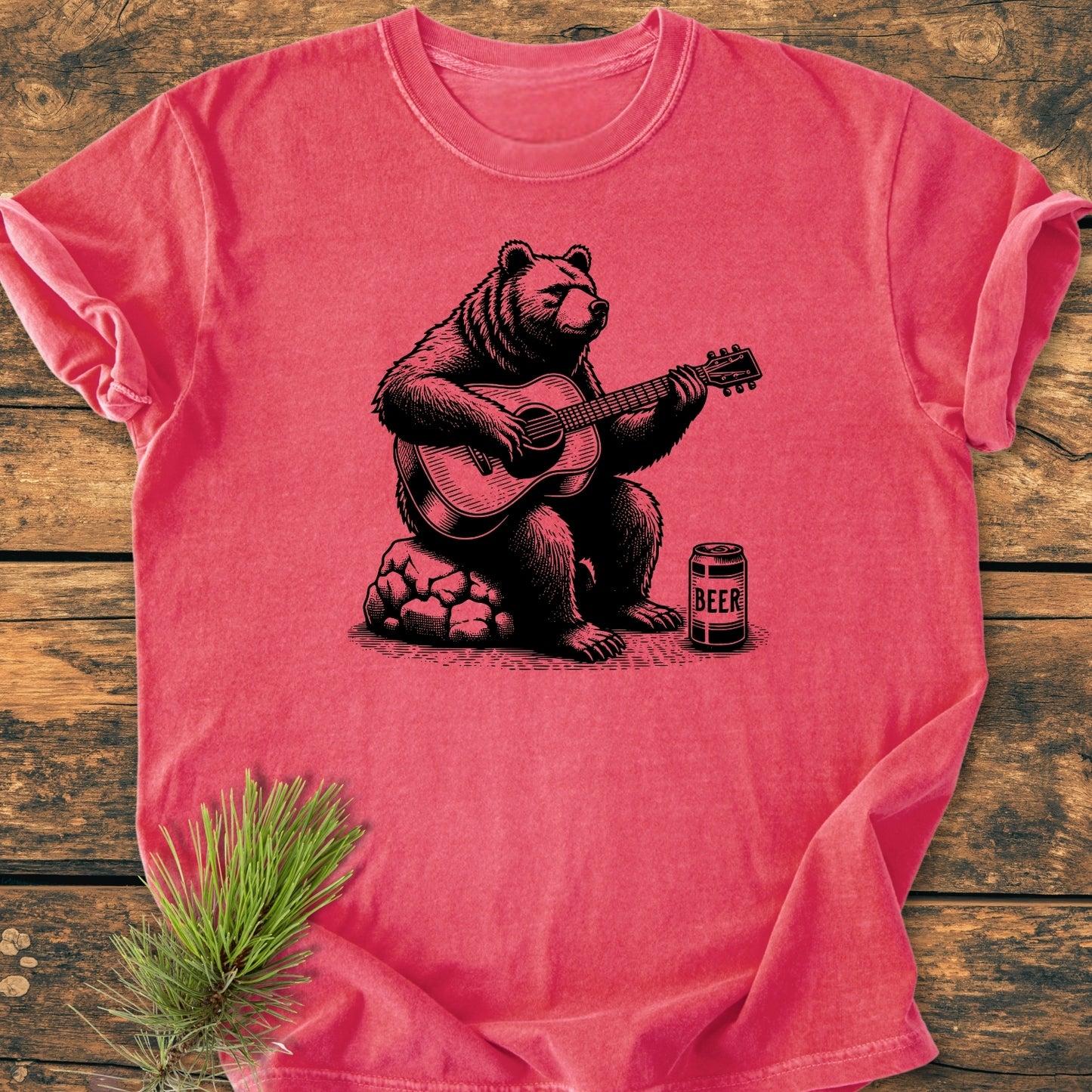 Bear Playing Guitar - Vintage Wash Tee features a bear line-drawing playing guitar next to a BEER can, printed on a soft, durable, pre-shrunk, ring-spun cotton tee laid on wood.