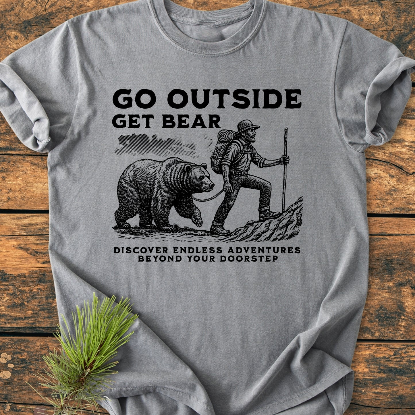 Heather-grey Go Outside Get Bear - Vintage Wash Tee showcasing a bearded hiker with a bear on a leash, crafted for adventure lovers. Features vintage-style print, relaxed fit, and durable cotton fabric.