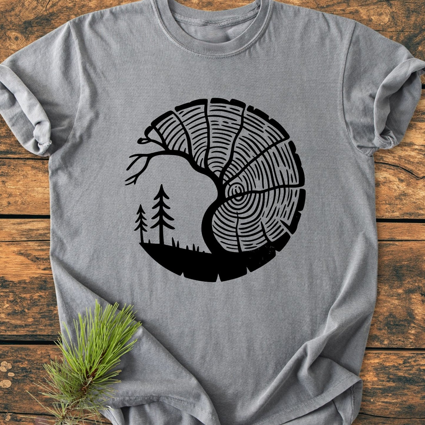 Tree Lover - Vintage Wash Tee features a circular tree trunk graphic transitioning into a forest silhouette, displayed on a soft, heather-gray T-shirt, highlighting its cozy, relaxed fit.