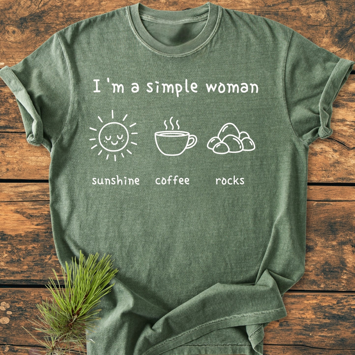 Sunshine, Coffee, Rocks - Vintage Wash Tee features a white print of a sun, coffee cup, and rocks. It’s laid on wood with a pine sprig, showcasing its relaxed fit and durability.