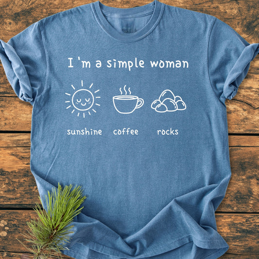 Heather-blue Sunshine, Coffee, Rocks - Vintage Wash Tee displayed flat on rustic wood, featuring white line art of a sun, coffee cup, and stones with captions. Cozy, relaxed fit, emphasizing garment-dyed, ring-spun cotton.