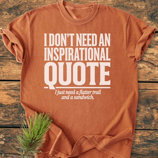 No Inspirational Quote - Vintage Wash Tee: A rust-orange T-shirt with bold white lettering humorously requesting a flatter trail and a sandwich, laid flat on a wooden surface with a pine sprig nearby.