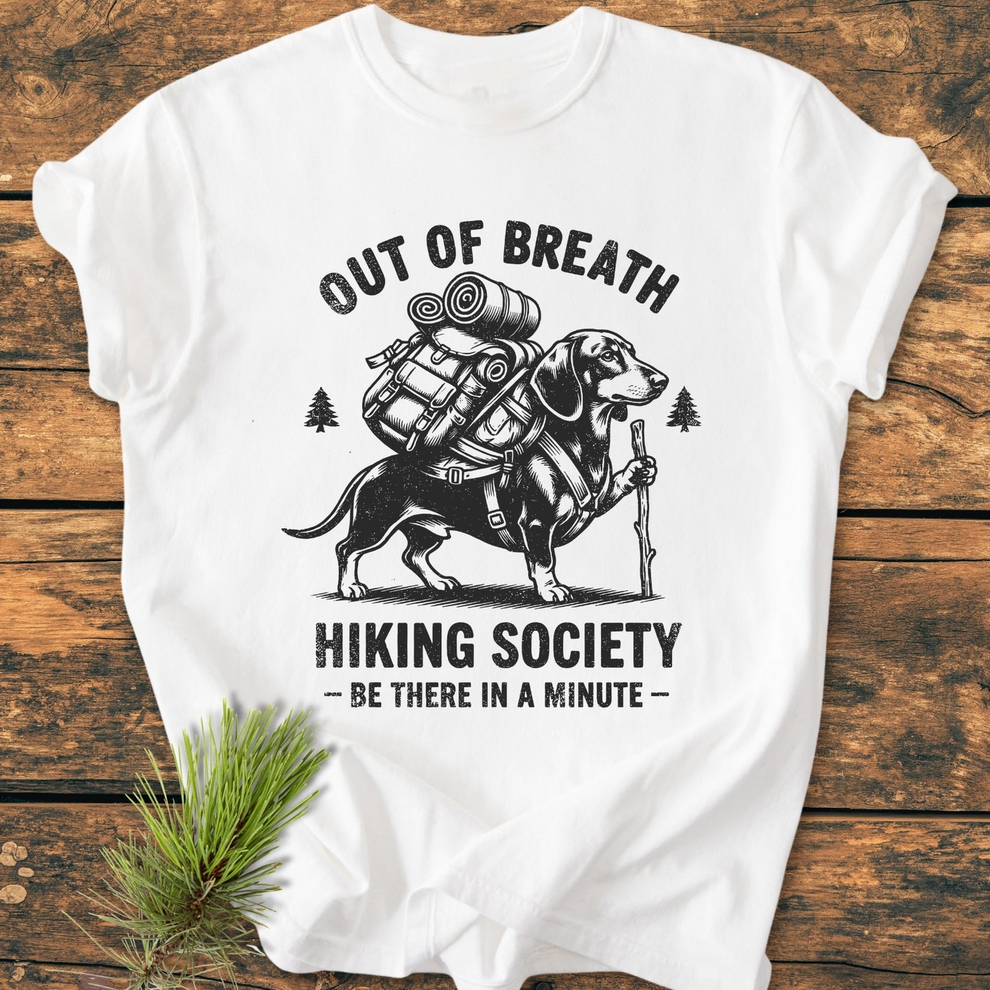 Out Of Breath Dachshund - Vintage Wash Tee featuring a dachshund with a backpack and hiking stick, framed by pine trees, on a white garment-dyed, ring-spun cotton shirt, offering a relaxed fit.