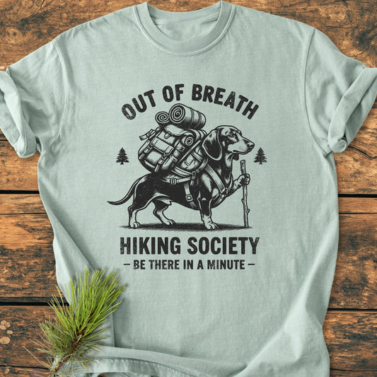 Out Of Breath Dachshund - Vintage Wash Tee features a cartoon dachshund with a backpack and hiking staff, surrounded by hiking-themed text and pine icons, showcasing a relaxed fit and durable stitching.