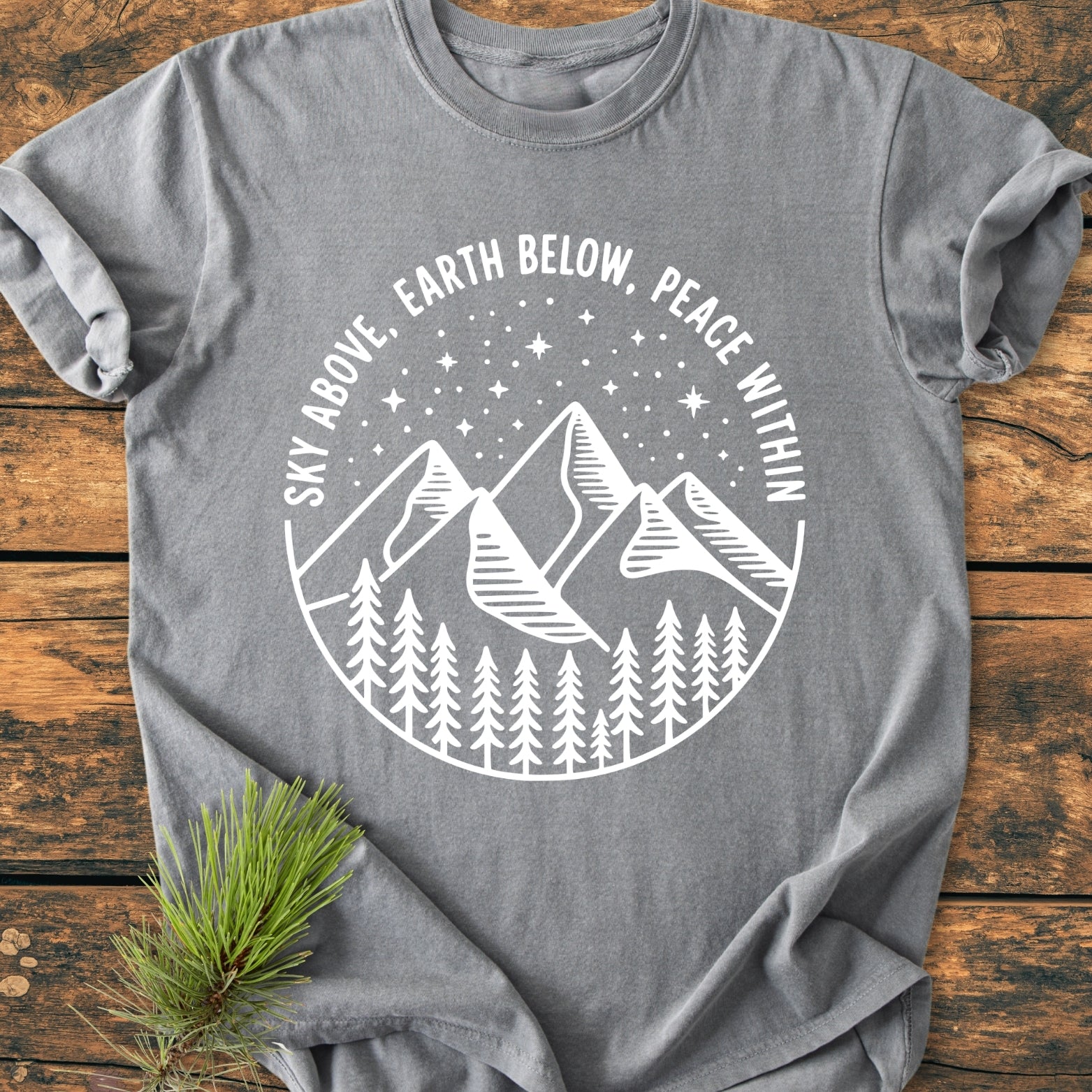 Sky Above - Vintage Wash Tee features a nature-themed graphic with pine trees, mountains, and stars. Crafted from soft, garment-dyed cotton, it offers a relaxed fit for everyday comfort.