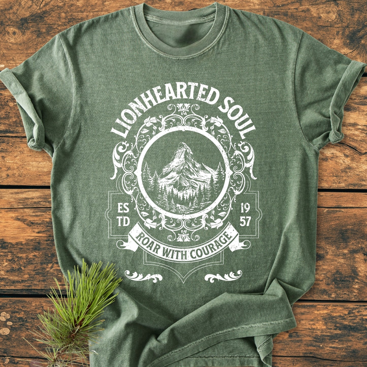 Lionhearted Soul - Vintage Wash Tee, featuring white vintage emblem with mountain and pine design, laid flat with pine sprig for styling; crafted from soft, durable, garment-dyed 100% ring-spun cotton.