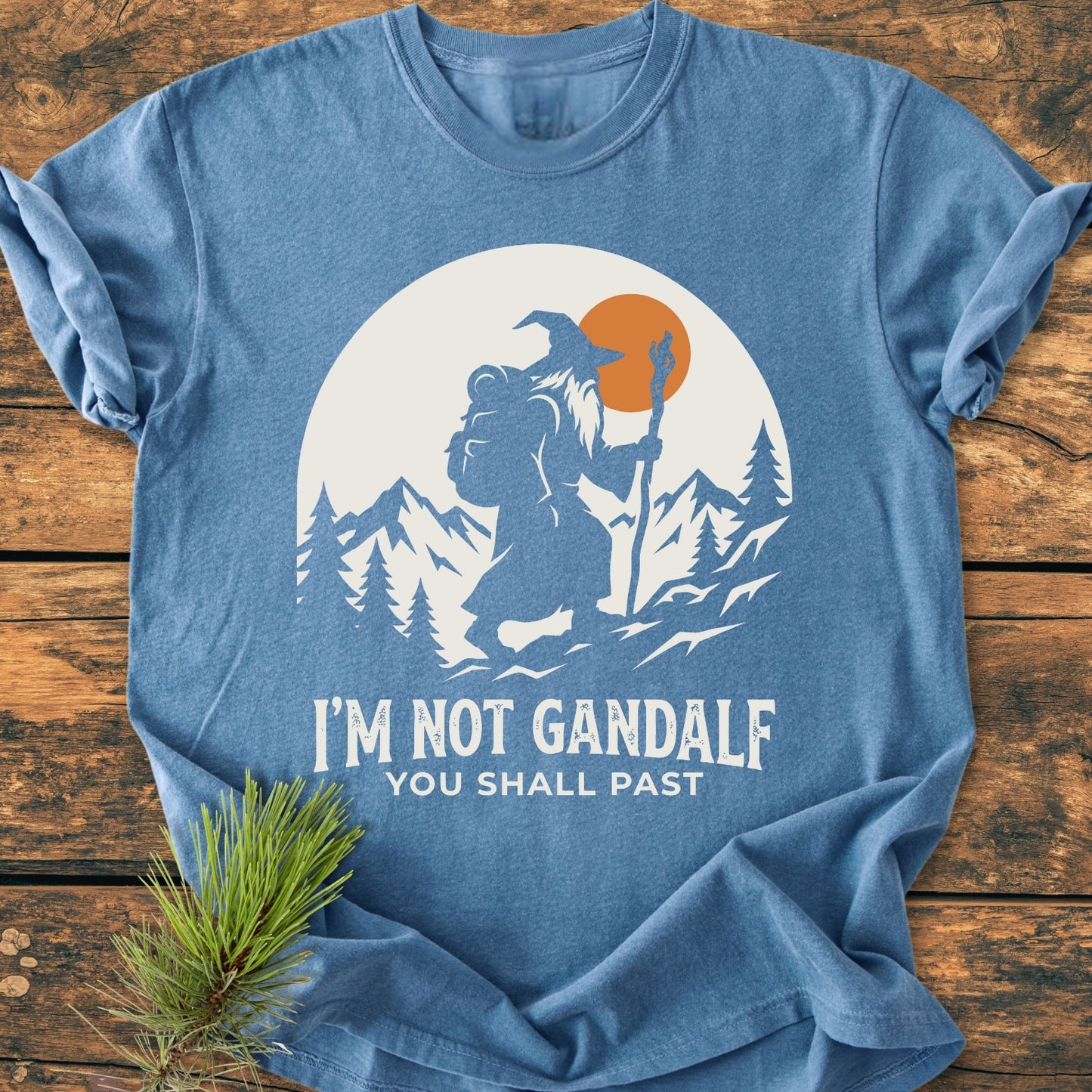 You Shall Past - Vintage Wash Tee features a whimsical wizard graphic and pun slogan, laid on wood. Crafted from soft, durable cotton, this relaxed-fit shirt offers cozy, everyday style.