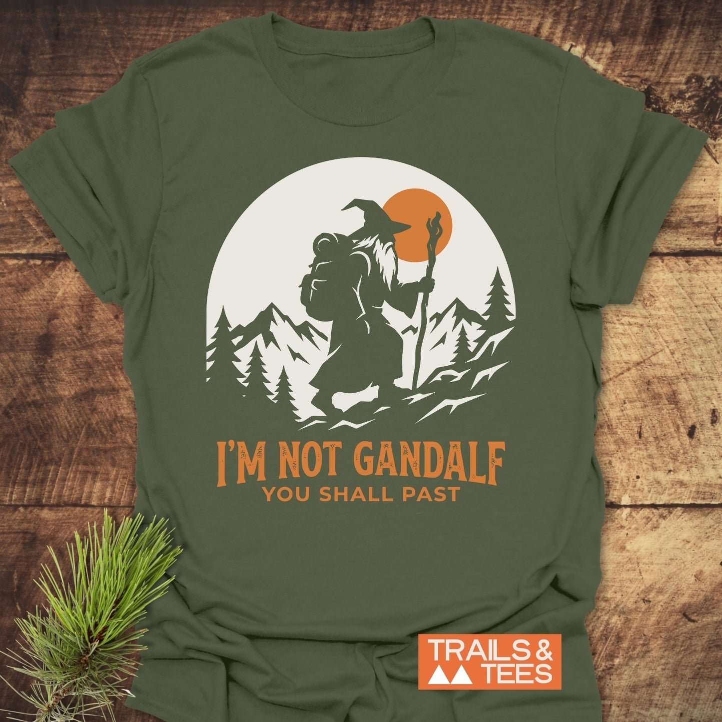 You Shall Past T-Shirt featuring a bearded wizard with a backpack and staff, trekking through mountains and trees, with “I’M NOT GANDALF – YOU SHALL PAST” slogan and Trails & Tees logo.