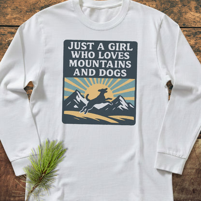 Just A Girl Who Loves Dogs Comfort Colors Long-Sleeve Tee featuring a mountain and dog graphic, laid on wood with pine branch, made from soft, 100% ring-spun cotton for a relaxed fit.