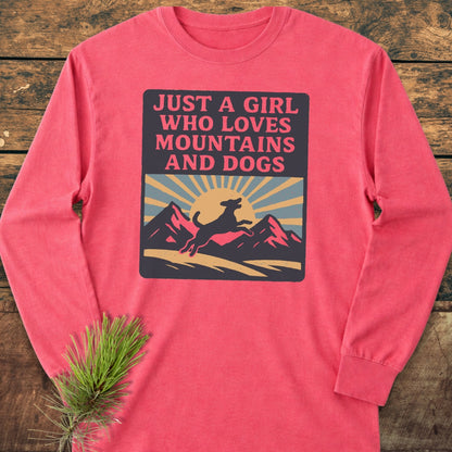 Just A Girl Who Loves Dogs Comfort Colors Long-Sleeve Tee featuring a sunrise and dog graphic, laid flat on wood. Made from soft 100% ring-spun cotton with a relaxed fit for comfort.