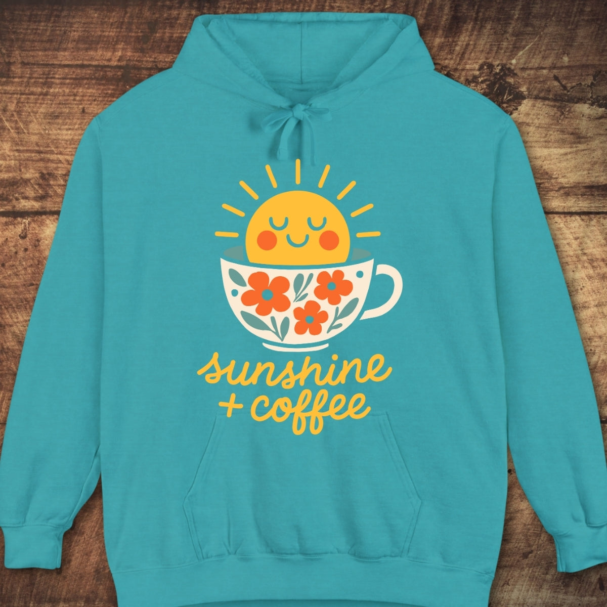 Sunshine And Coffee Hoodie with a cheerful sun and teacup graphic, featuring sunshine + coffee text. Laid flat, showcasing its relaxed fit and garment-dyed fabric, perfect for cozy, everyday comfort.