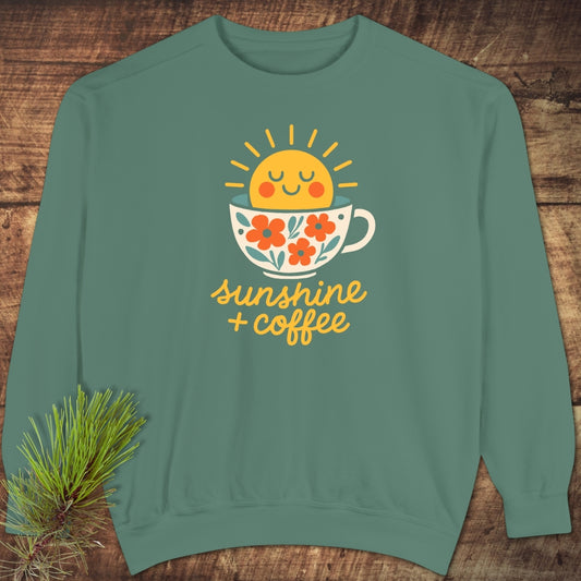 Sunshine And Coffee Sweatshirt featuring a playful sun and coffee cup graphic on a teal-green crewneck, showcasing luxurious comfort with a relaxed fit, highlighted by a pine sprig accent.