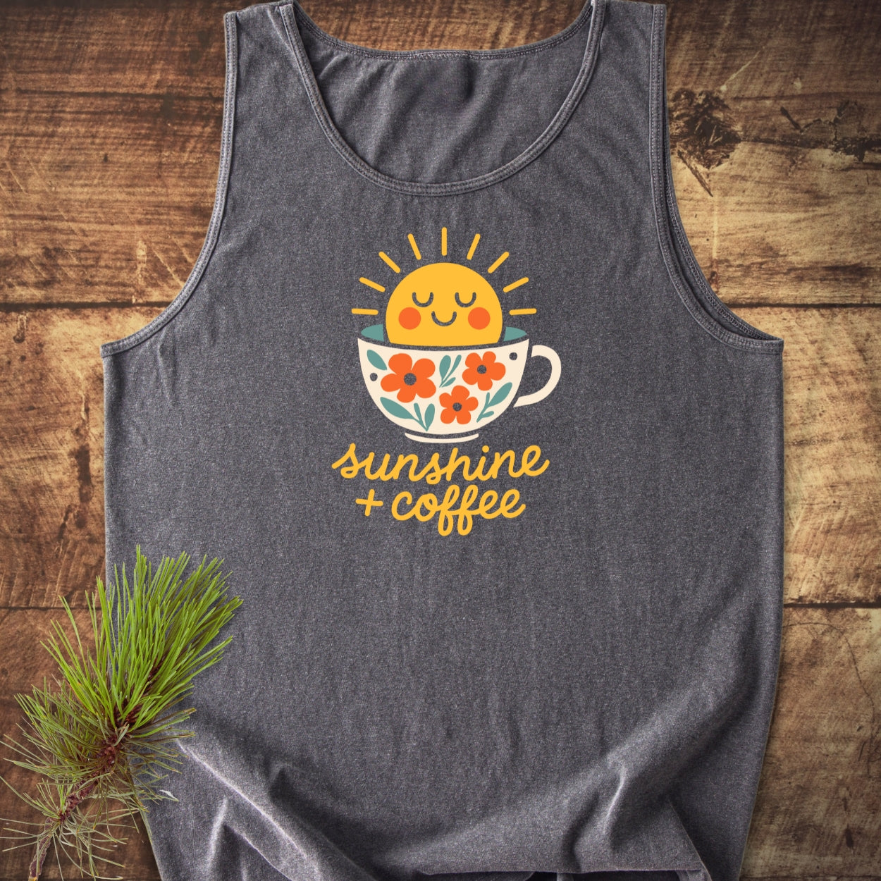 Sunshine And Coffee Tank Top featuring a cheerful sun and coffee cup graphic on dark-gray fabric, laid on wood. Made from 100% US cotton, showcasing eco-friendly dyes and relaxed fit.