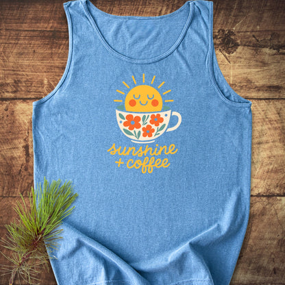 Sunshine And Coffee Tank Top featuring a smiling sun graphic in a floral coffee cup, laid on wood with a pine sprig. Made from sustainable, 100% ring-spun US cotton for a relaxed fit.