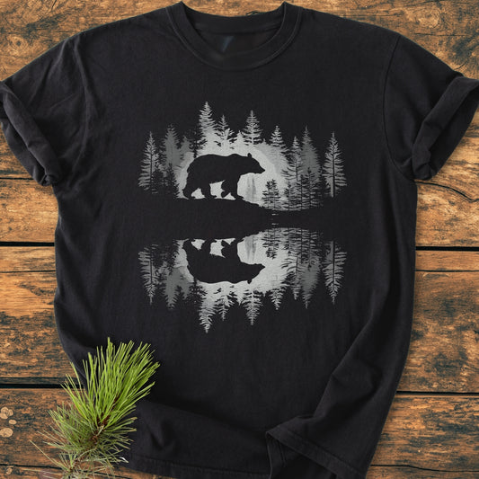 Bear Reflection - Vintage Wash Tee on a wooden backdrop, features a bear and forest graphic mirrored like a water reflection. Made from soft, ring-spun cotton, ideal for comfort and durability.