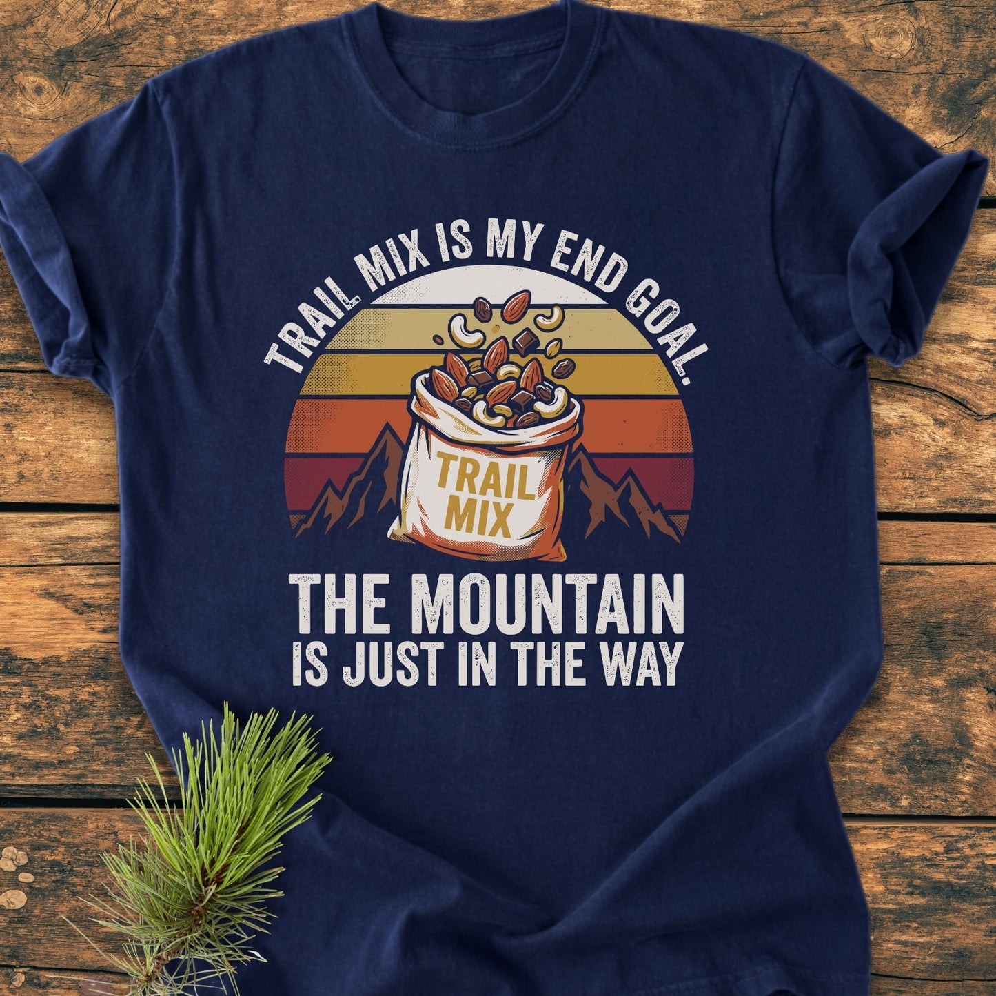 Trail Mix End Goal - Vintage Wash Tee features a retro mountain graphic with a vibrant sun, accented by a trail mix bag, on a navy-blue backdrop, highlighting comfort and durability.