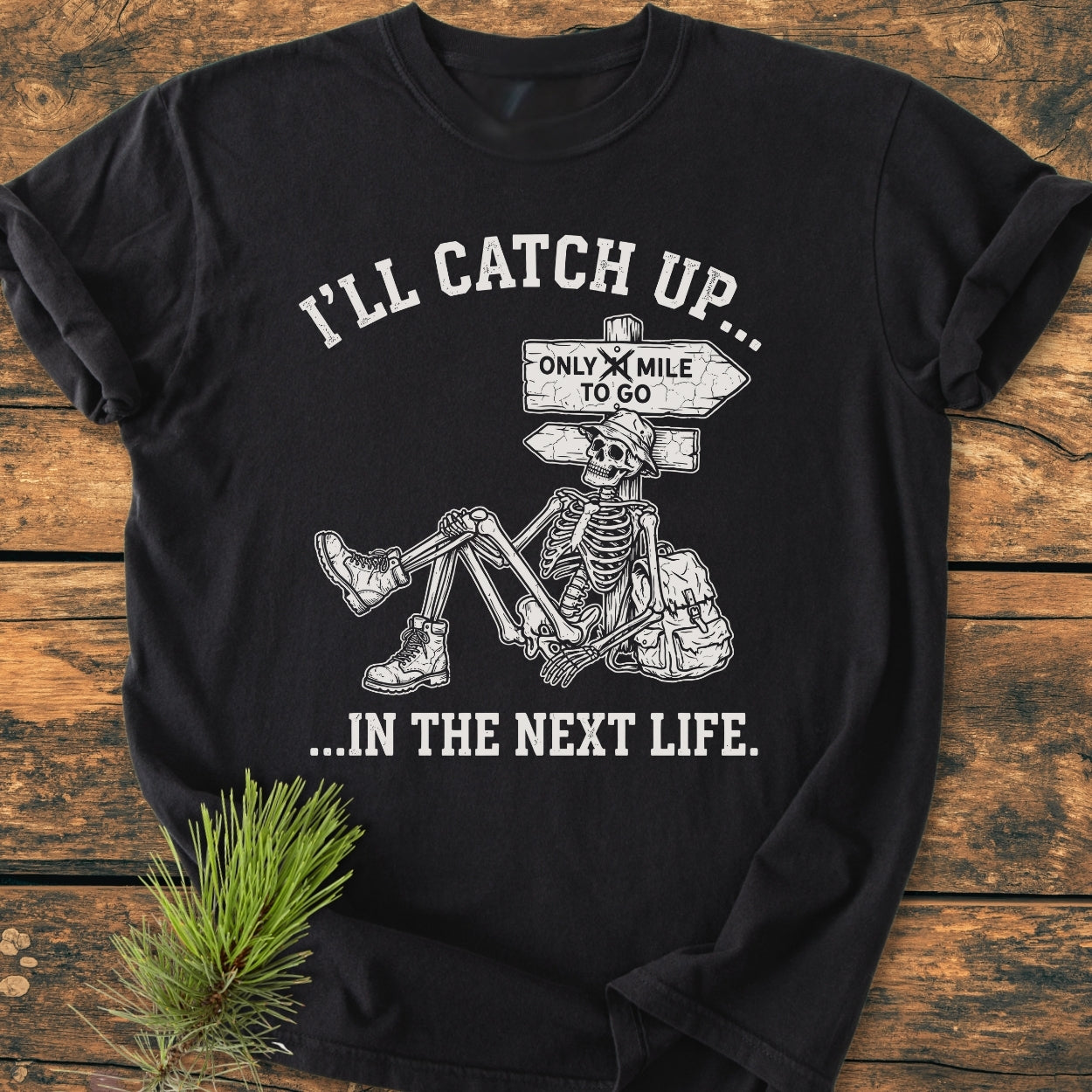 I'll Catch Up - Vintage Wash Tee features a cartoon skeleton with hiking gear and humorous text. Laid on wood, this black, relaxed-fit tee offers comfort and style with durable, garment-dyed fabric.
