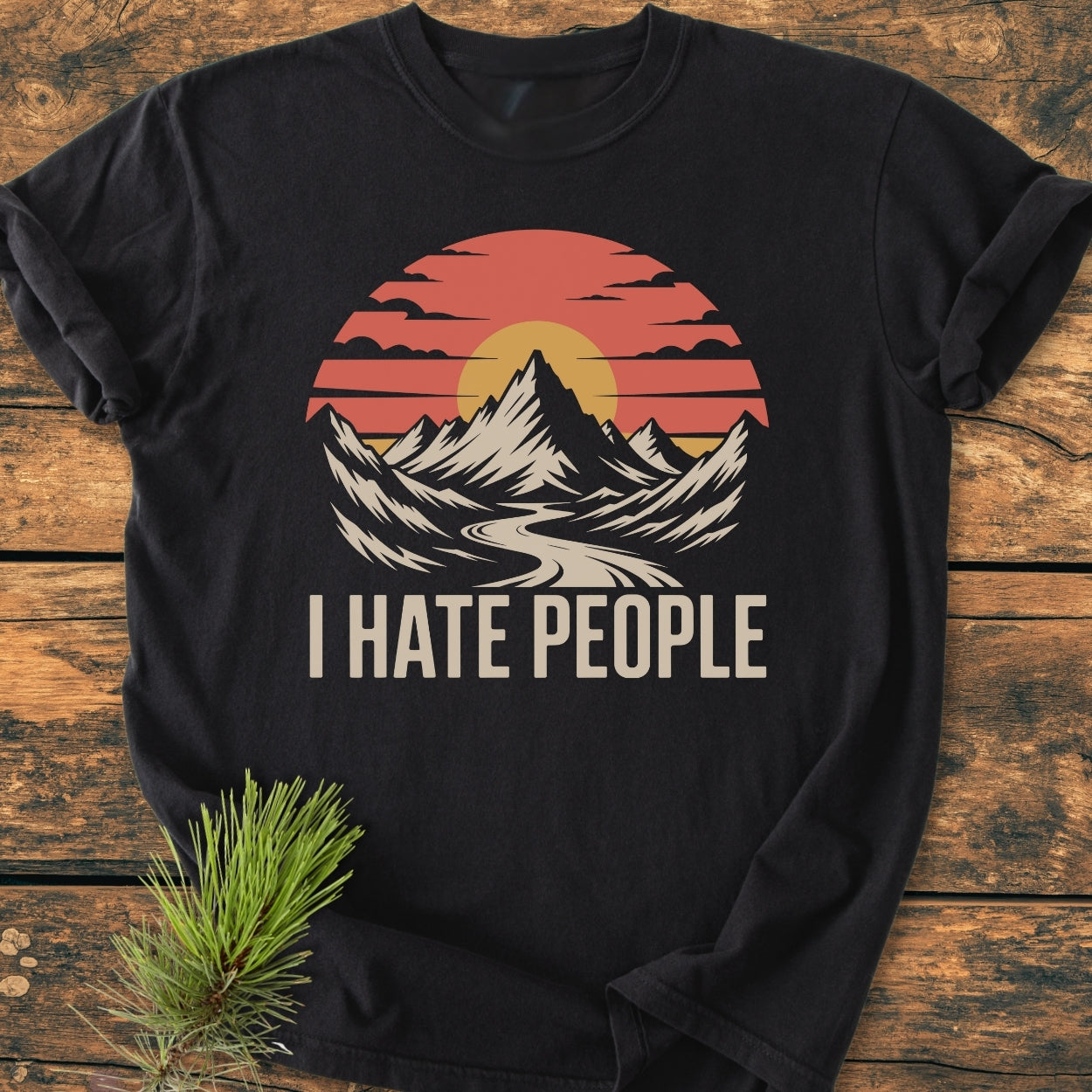 I Hate People - Vintage Wash Tee with mountain graphic and bold text, laid flat on wood, showcasing its relaxed fit and soft-washed 100% ring-spun cotton fabric for ultimate comfort.