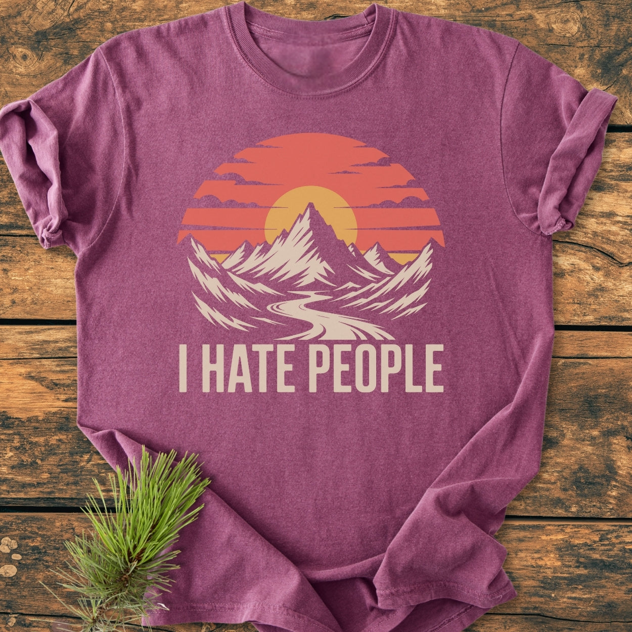 Heather-purple I Hate People - Vintage Wash Tee with a mountain-and-river scene and orange sun graphic, laid flat on wood. Made of soft-washed, pre-shrunk 100% ring-spun cotton, offering a relaxed fit.