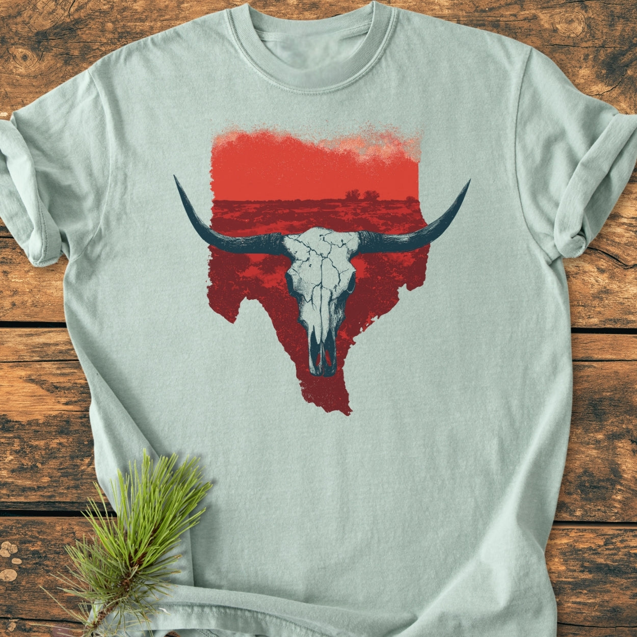 Hike Texas - Vintage Wash Tee features a red Texas silhouette with a white longhorn skull print, laid on a wooden surface. Crafted from soft, garment-dyed cotton for comfort and durability.