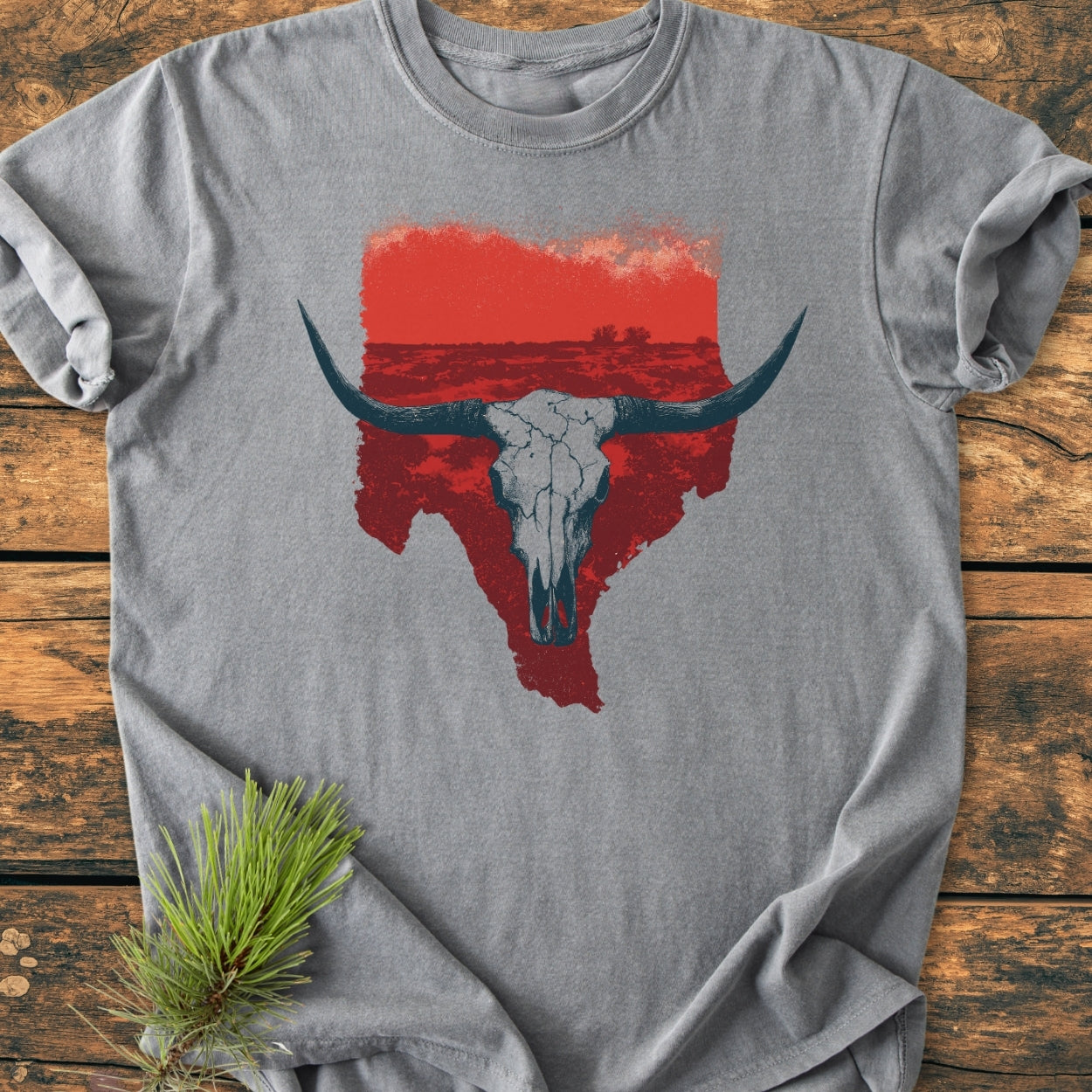 Hike Texas - Vintage Wash Tee: Heather-gray T-shirt with a distressed red Texas outline and cracked longhorn skull graphic, laid on wood. Cozy, relaxed fit with durable double-needle stitching, perfect for everyday wear.